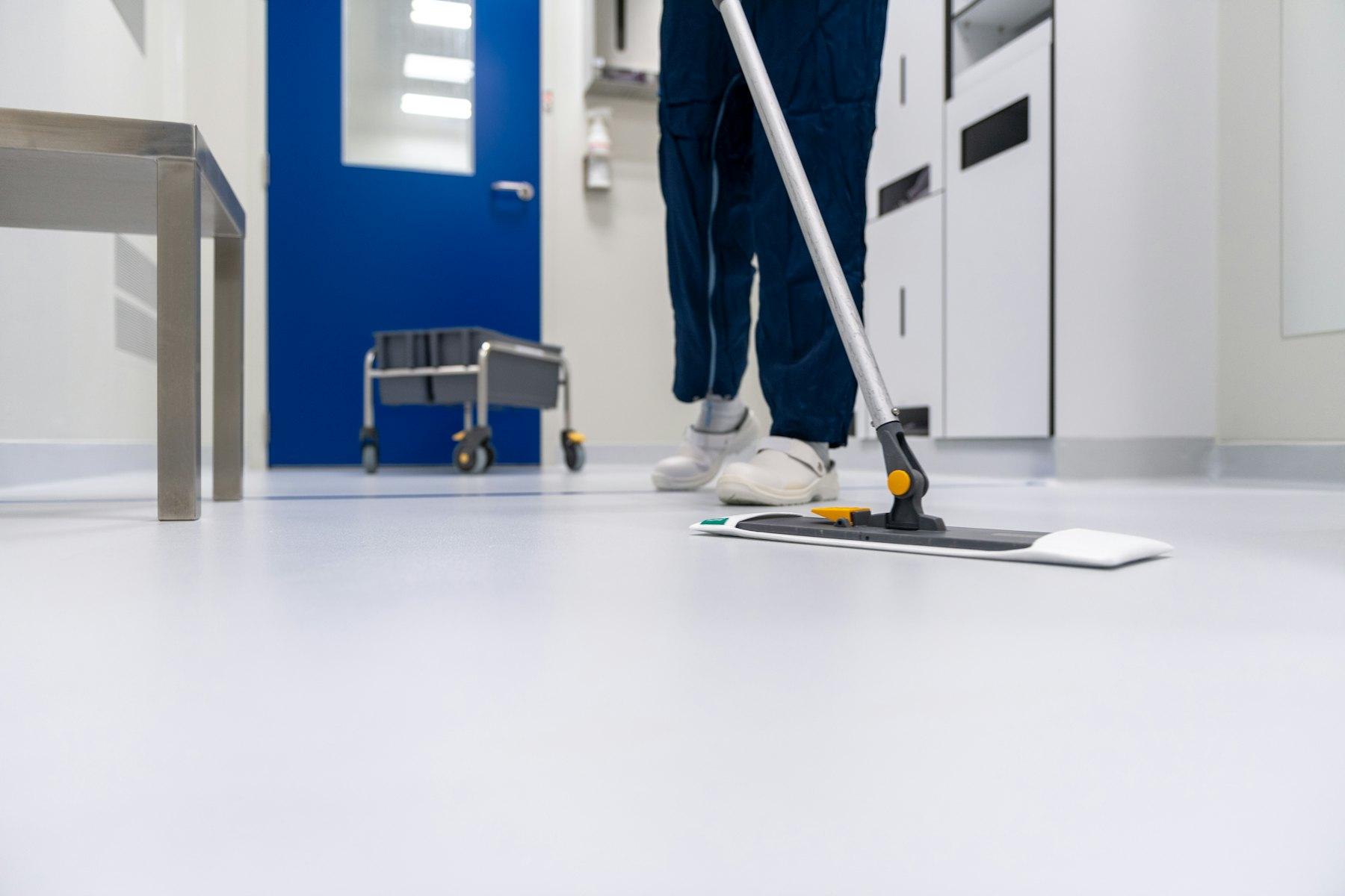 Cleaner mopping a bright white corridor