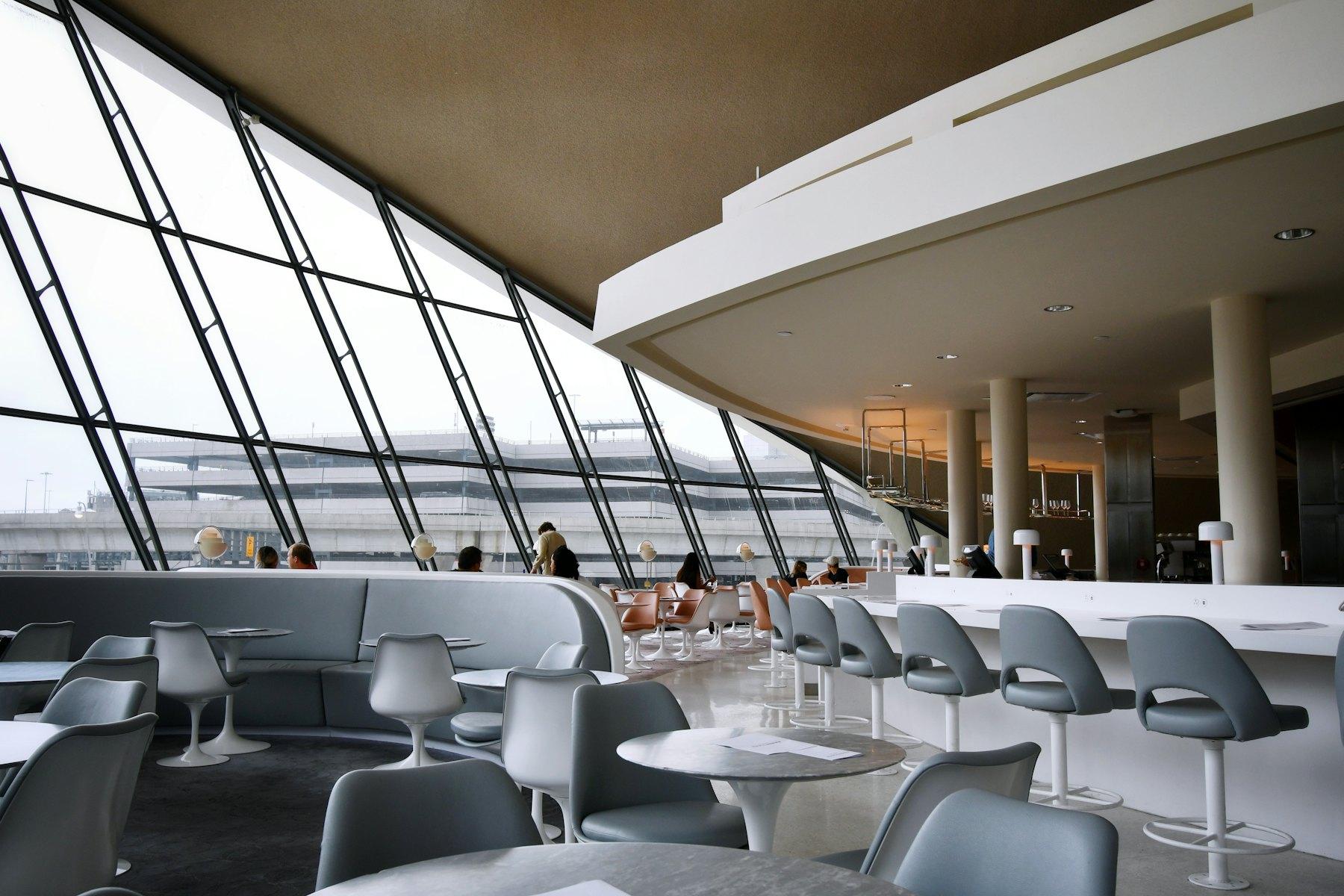Bright airport departure lounge with seating along floor-to-ceiling windows
